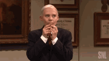 a man in a suit and tie eating a sandwich with a snl logo on the bottom right