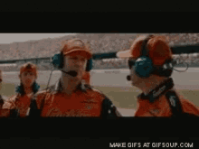 a group of men wearing headphones are watching a race on a track ..