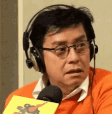 a man wearing headphones and glasses holds a microphone