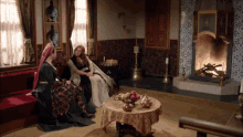 three women sitting in front of a fireplace in a room