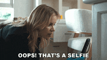 a woman taking a selfie with the words oops that 's a selfie behind her