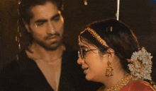 a man and a woman are standing in the rain and the woman is wearing glasses