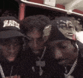 a group of three men wearing hats and necklaces are posing for a picture .