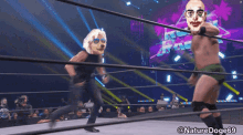 a wrestler with a clown face on his head is fighting another wrestler with a dog face on his head