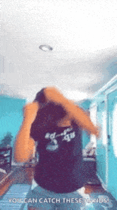 a woman in a black shirt is dancing in a living room with her hands in her hair .