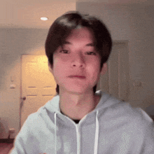 a young man wearing a hoodie is looking at the camera in a room .