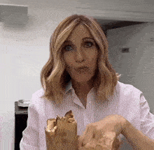 a woman in a striped shirt is holding a sandwich