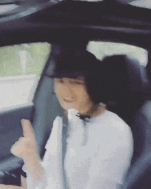 a woman in a white shirt is giving a thumbs up while sitting in a car