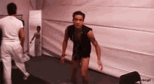 a man in a black vest is standing in front of a wall with a rbd.gif watermark