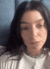a close up of a woman wearing a white shirt and a silver necklace