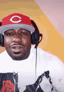 a man wearing headphones and a red hat with a white letter c on it