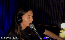 a woman wearing headphones singing into a microphone with the name maryle mar written on the bottom
