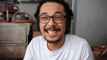 a man wearing glasses and a white shirt smiles