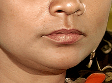 a close up of a woman 's face with her mouth open and earrings