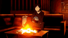 a man sitting on a couch holding a deck of cards with a fire in the background