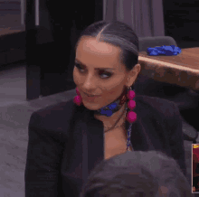 a woman wearing earrings and a scarf around her neck is smiling