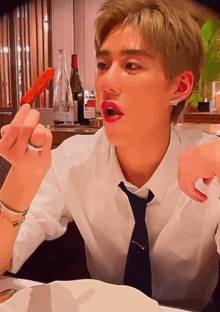 a man with red lipstick on his lips is sitting at a table eating food