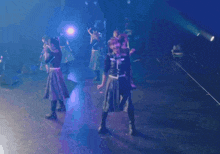 a group of women are dancing on a stage with purple lights behind them