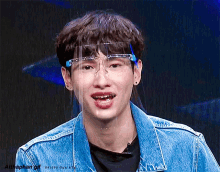 a young man wearing a face shield and glasses is smiling