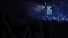 a man singing into a microphone in front of a crowd with their hands in the air