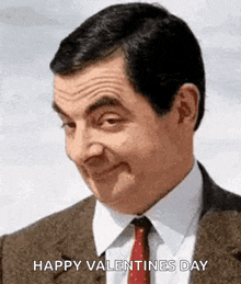 mr bean is wearing a suit and tie and is smiling .