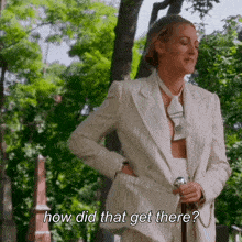 a woman in a white suit and tie is holding a cane and asking how did that get there
