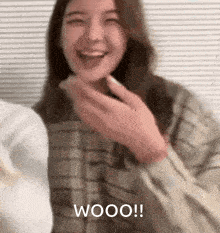 a woman is laughing and covering her mouth with her hand while a man looks on .