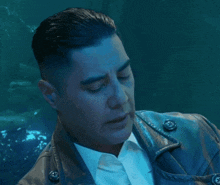 a man wearing a leather jacket and a white shirt is looking at the camera
