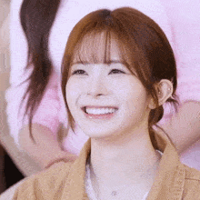 a close up of a woman 's face smiling with a necklace around her neck .
