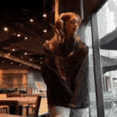 a woman wearing headphones is standing in front of a large window in a restaurant .
