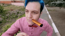 a man with blue hair and a pink shirt is blowing a trumpet