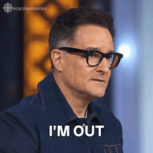 a man wearing glasses says i 'm out in front of a cbs dragonsden logo