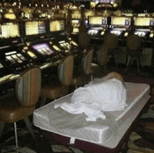 a person is laying on a mattress in front of slot machines