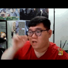 a man with glasses and a red shirt is making a funny face