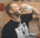 a man drinking from a glass with a star wars t-shirt on