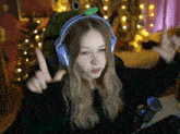 a girl wearing a frog hat and headphones is giving the middle finger