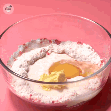 a glass bowl filled with powdered sugar eggs and butter has the word cake on it