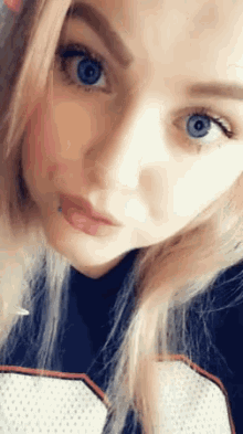 a close up of a woman 's face with blue eyes and a tattoo on her lip .