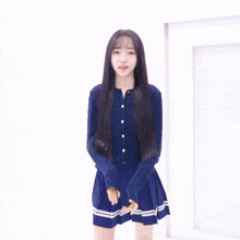 a girl with long black hair is wearing a blue sweater and making a heart with her hands