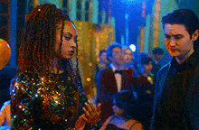 a woman in a sequined dress is standing next to a man in a tuxedo .