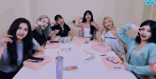 a group of girls sitting around a table with vlive written on the bottom right