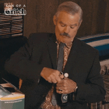 a man in a suit and tie holds a bottle of beer