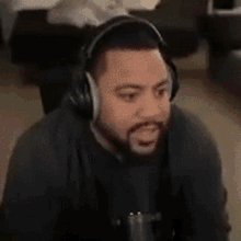 a man with a beard and headphones is sitting in front of a microphone .