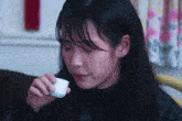 a woman is holding a small white container in her hand