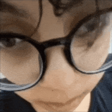 a close up of a person wearing glasses and a blue shirt