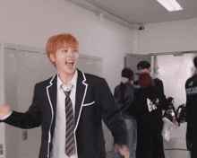 a man in a suit and tie is laughing in a room with lockers