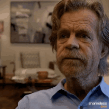 a man with a beard is wearing a blue shirt with the word shameless on it
