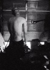 a man without a shirt is standing in front of a garage