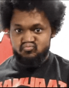 a man with a beard and curly hair is wearing a samurai shirt .
