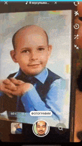 a phone screen shows a picture of a boy with the words " я мускулма " on the top left